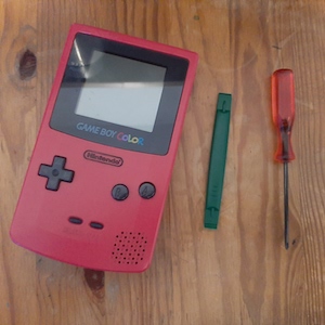 Game Boy Color, a spudger and a triwing screwdriver.