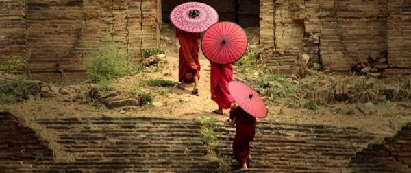 Three monks ascending the stairs of an ancient temple.