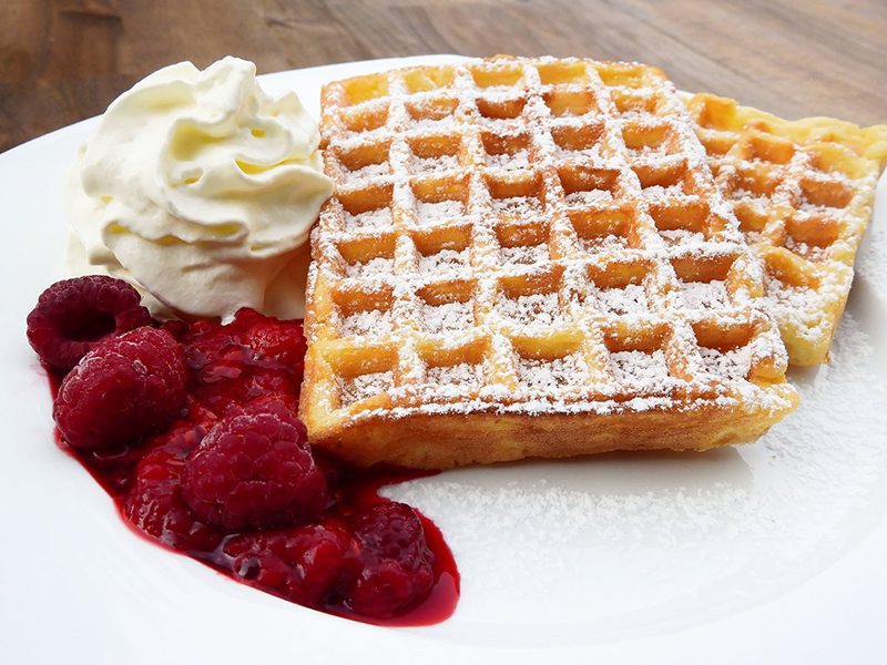 Waffles with raspberries and whipped cream.